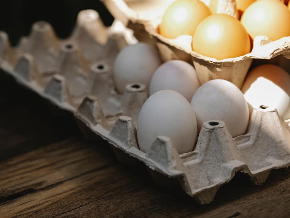 A carton of fresh eggs on a wooden kitchen table